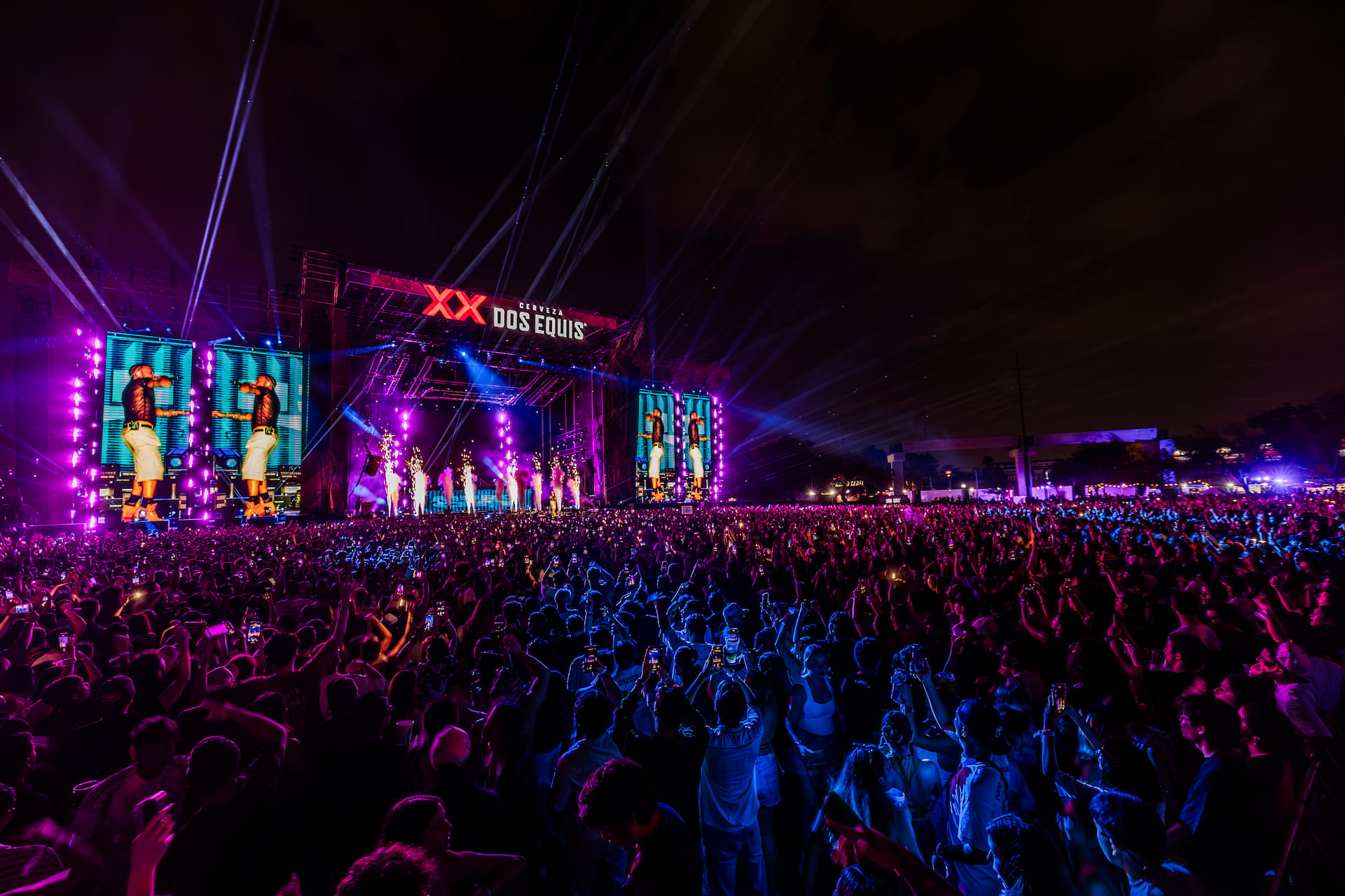 Escenario de Dale Mixx con luces violetas y publico al anochecer.